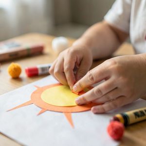 Zbliżenie rąk dziecka przyklejających promyk