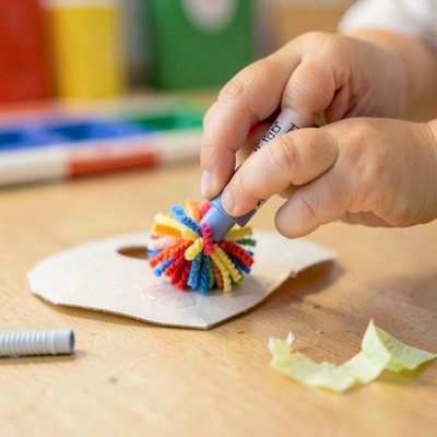 Zbliżenie rąk dziecka przyklejających pomponik