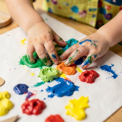 Zbliżenie rąk dzieci stemplujących farbą