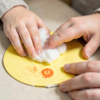 Zbliżenie: rączki przyklejają watę i elementy